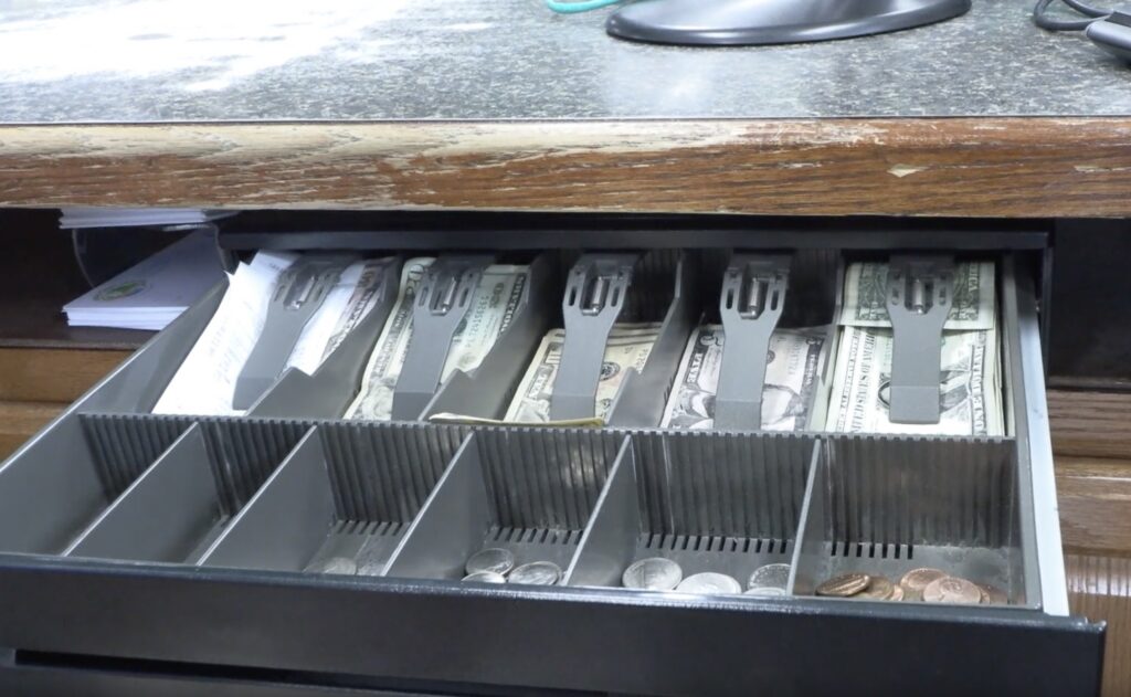 The inside of a cash register filled with bills and coins.