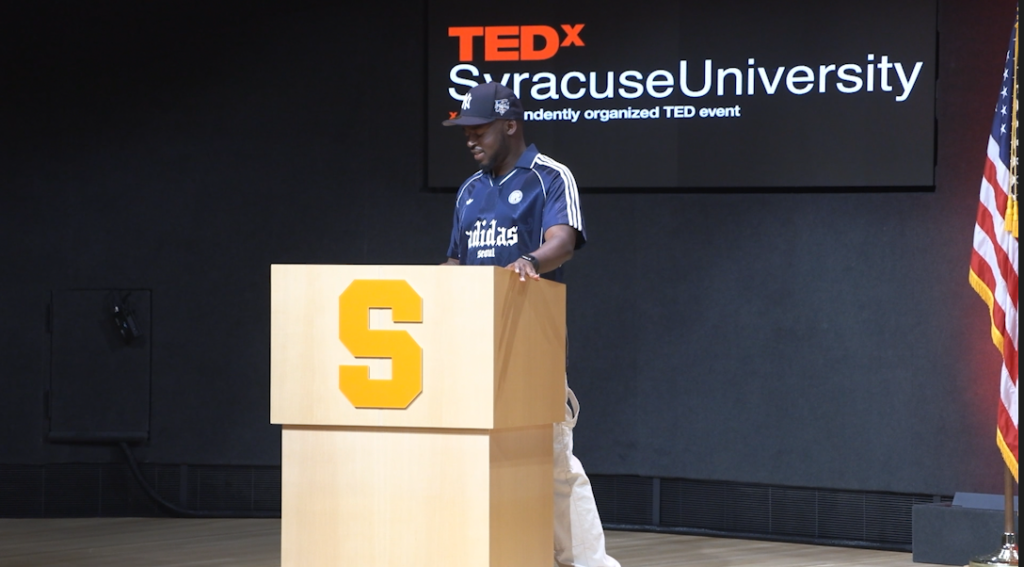 Syracuse TedX organizer Ryan Nkongnyu stands at a lectern.