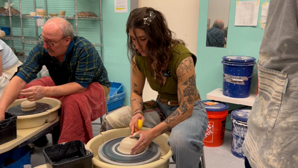 Marley Montague works on a pottery wheel to shape clay.