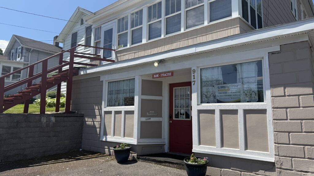 Tan and white building with maroon door where office for the National Alliance on Mental Illness is located in Syracuse, NY.