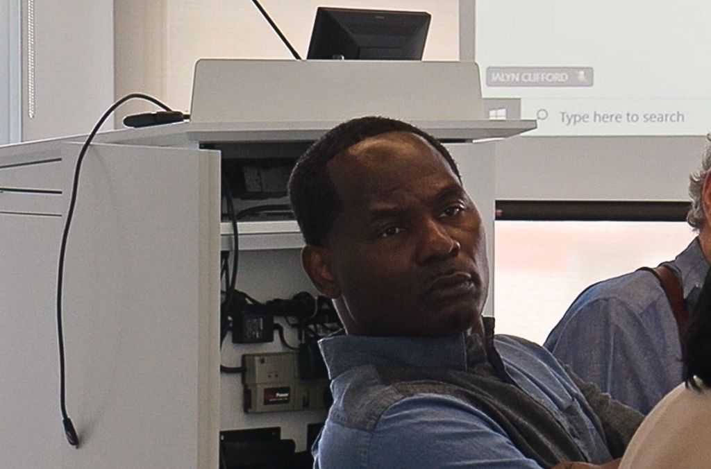 A man focused sitting in a chair looking at someone.