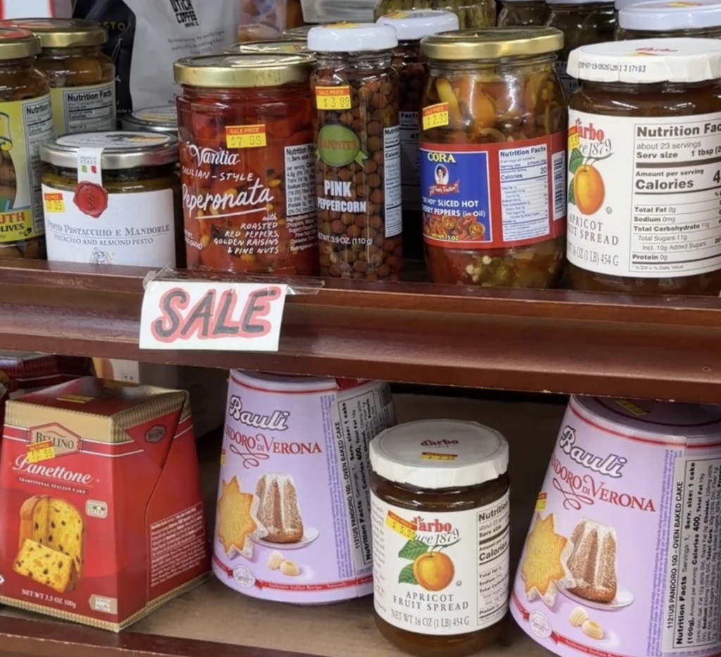 Sale shelf full of discounted Italian goods like hot peppers, olives, preservatives and pannetone