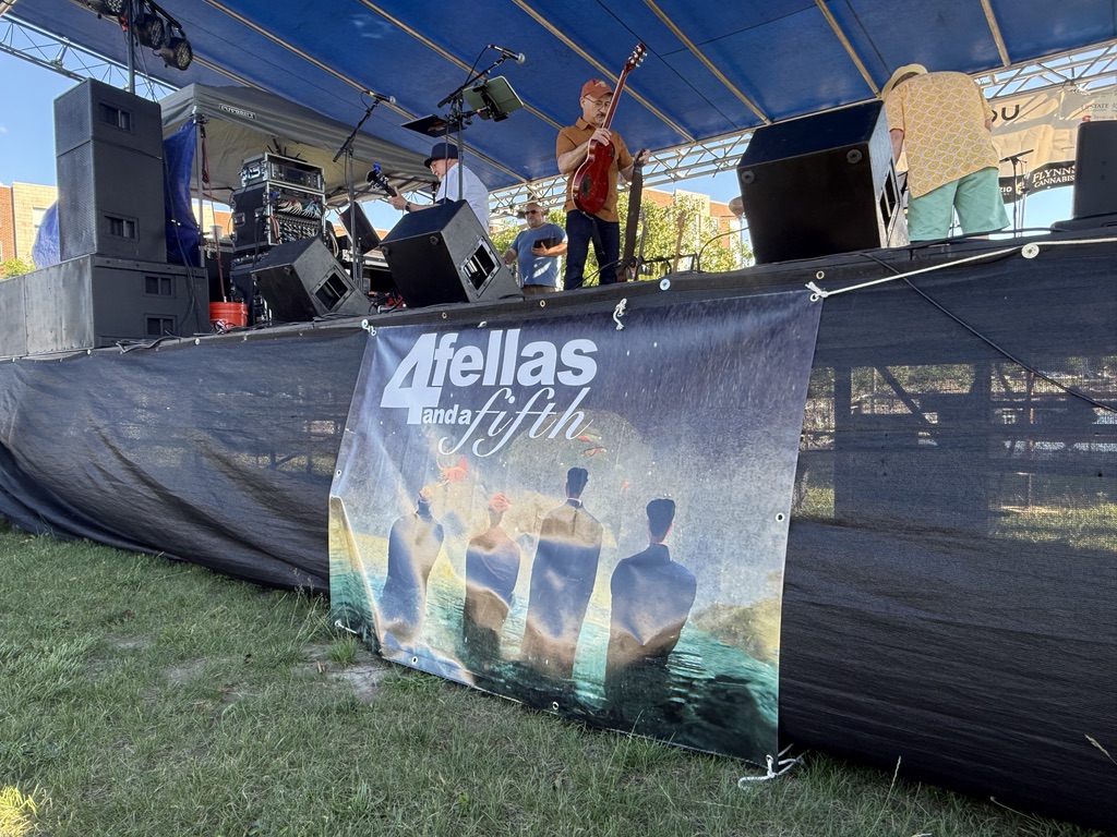 4 Fellas and a Fifth sign with band members walking around on stage holding guitars