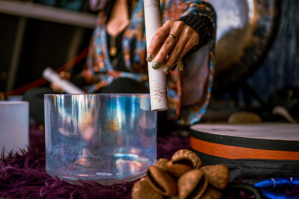A close up of a hand playing a crystal singing bowl. 