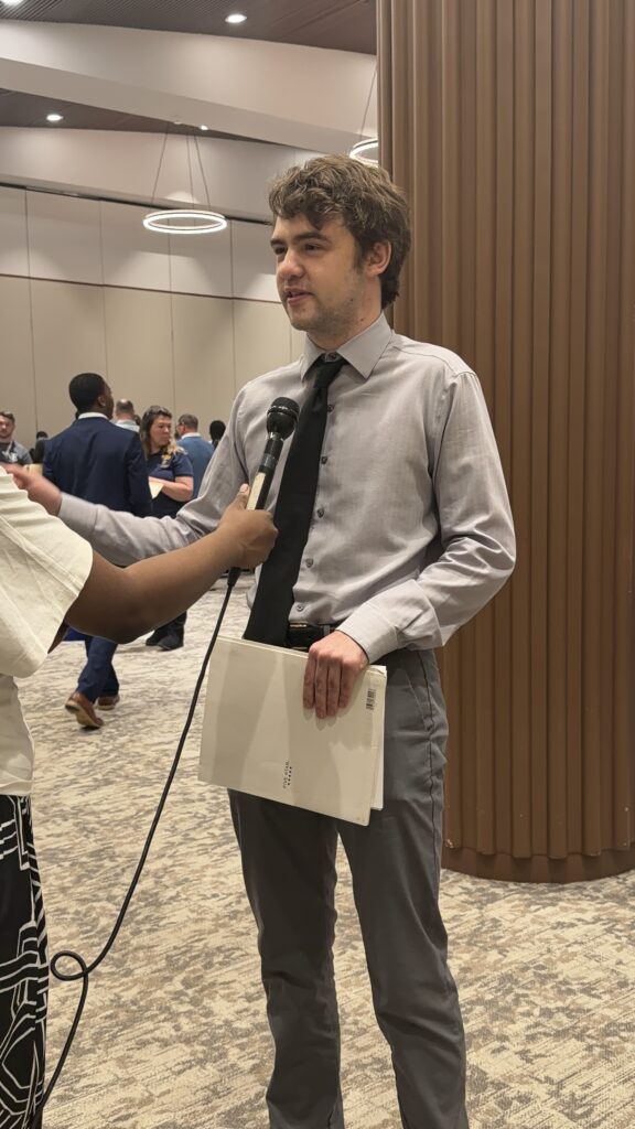 Young man standing being interviewed by reporter
