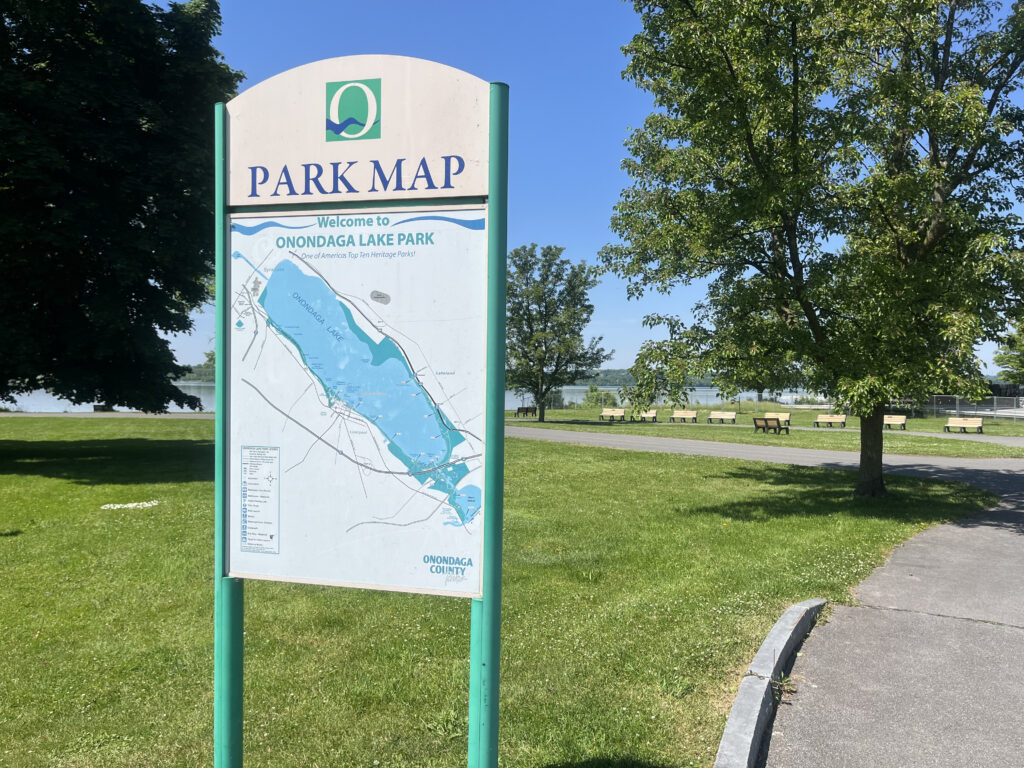 The white and green sign is the Onondaga Lake Park map that helps visitors to navigate where they want to go.