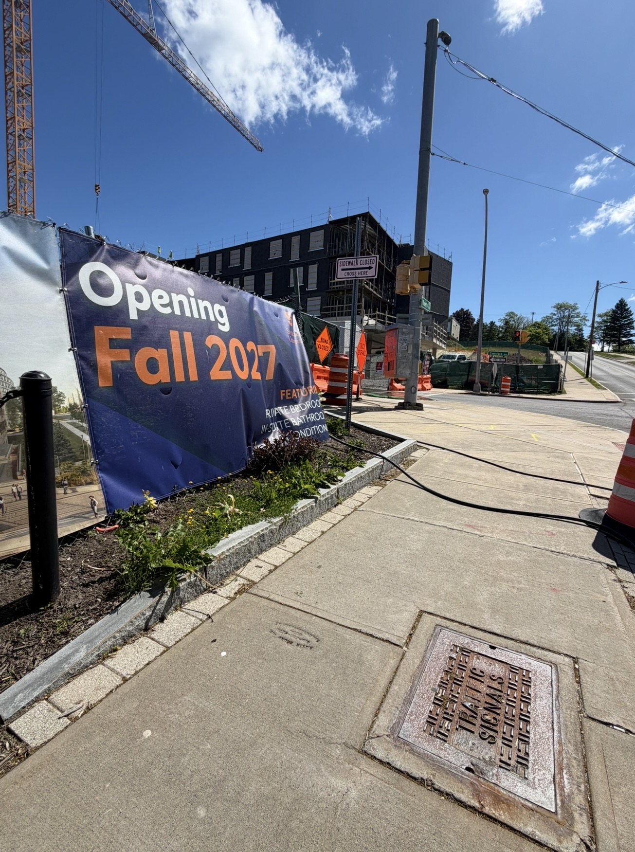 Sign on fence that says Opening Fall 2027 in front of construction site