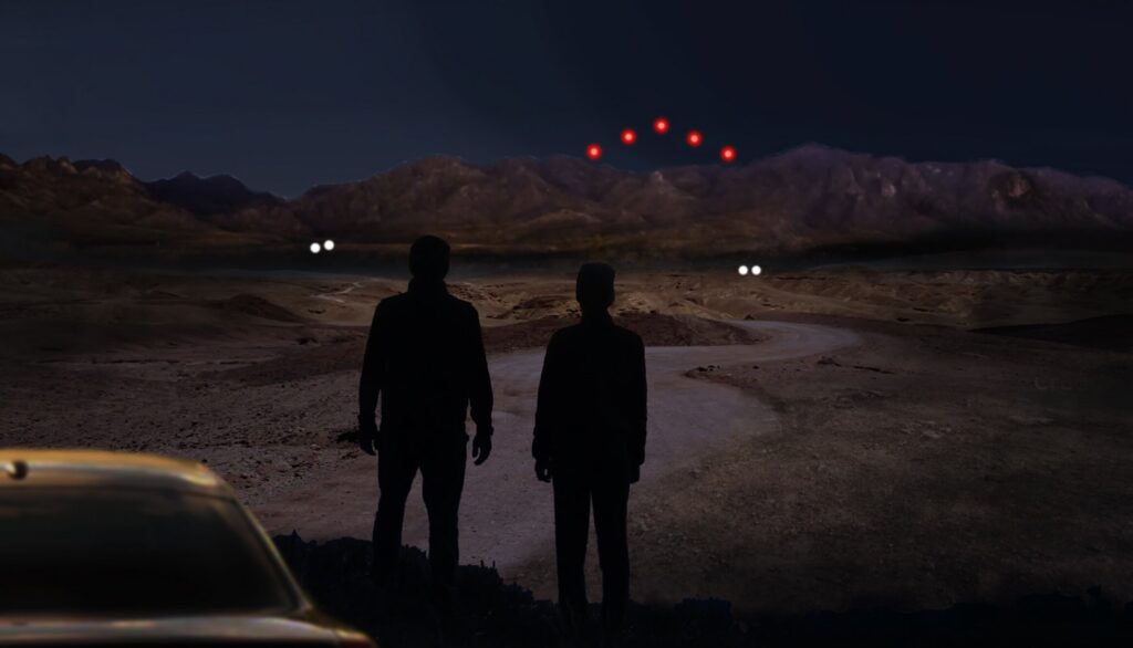 Artist's rendering of red orbs in the night sky over a desert, with two figures looking on.