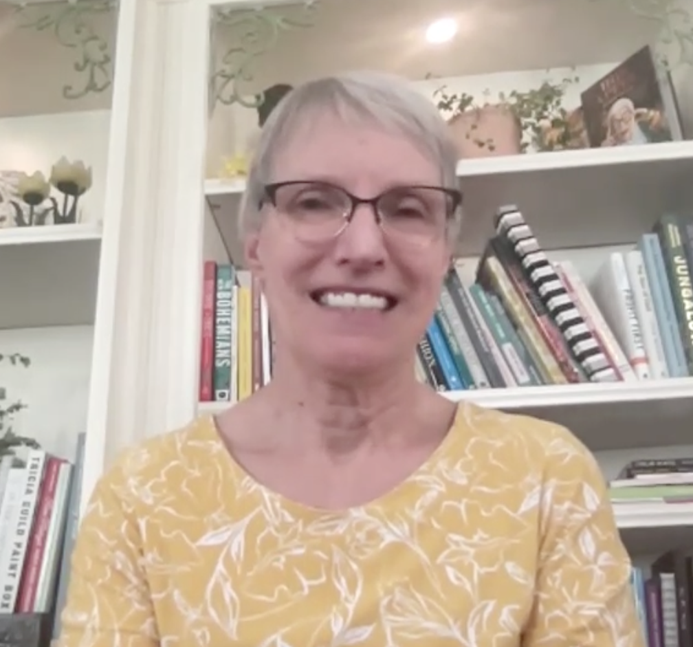 NYS Senator Rachel May smiles in front of a bookshelf