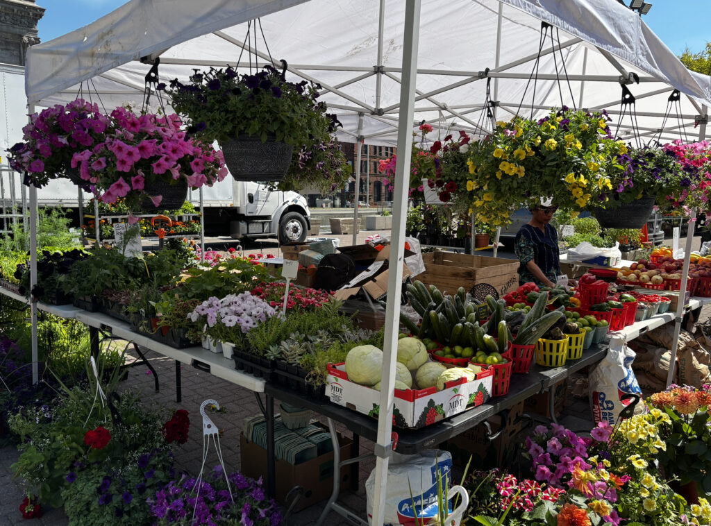 Fresh produce being sold under a tent at a farmers market