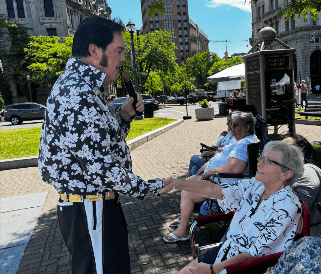 A performer holds the hand of one of the attendees at the public concert