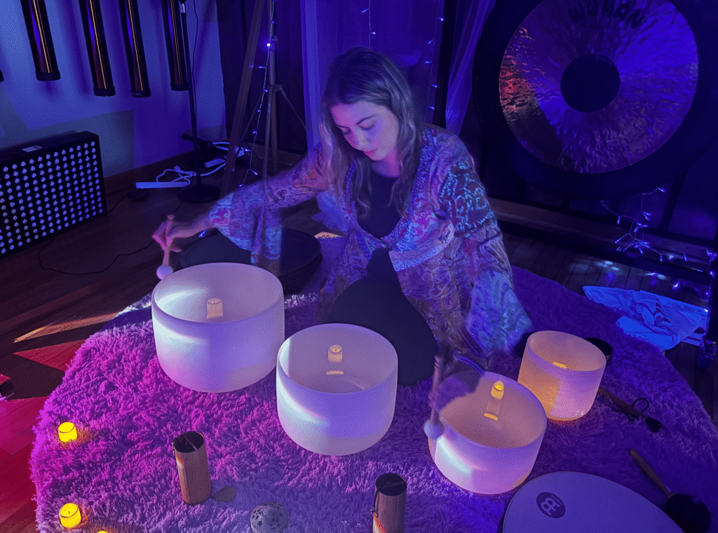 A sound bath practitioner plays a crystal singing bowl.