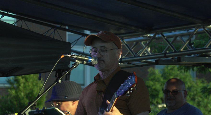 Man singing at microphone while playing guitar
