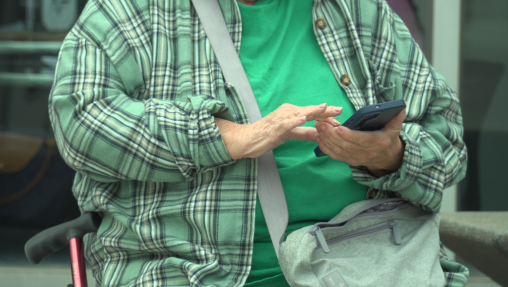 Older ticketholder scrolls on her phone. 