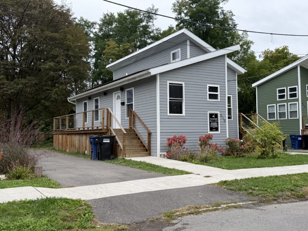 A tiny home on a yard with flowers.