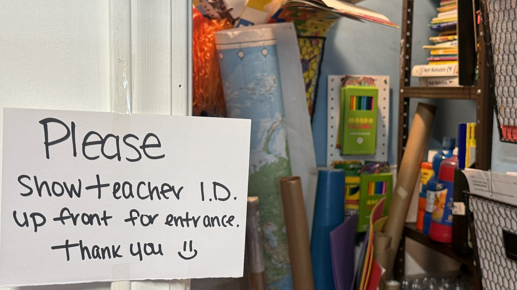 White sign reads "Please show teache I.D. up front for entrance. Thank you" in front of a closet full of art supplies.